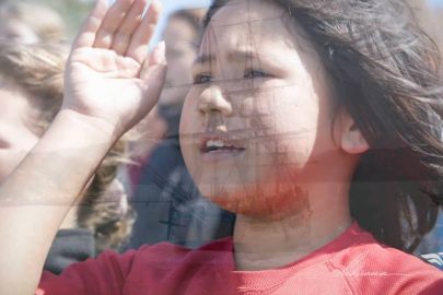 Screenshot taken from Tuia 250 video. Double exposure of young children welcoming and flotilla arriving