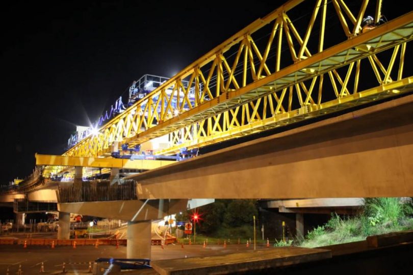 Night time shot of bridge steelwork being moved into place as part of the Waterview Connection
