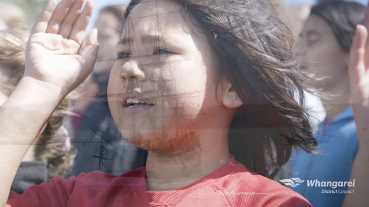 Screenshot taken from Tuia 250 video. Double exposure of young girl welcoming and flotilla arriving